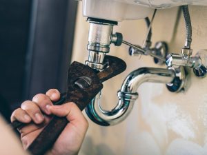 picture of a plumber fixing sink drainage with a wrench