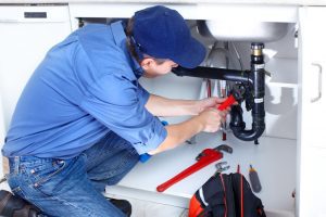 photo of a professional plumber while repairing a broken drain