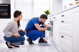 customer watching the plumber while fixing broken sink drain