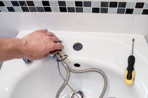 plumber installing faucet in a sink picture